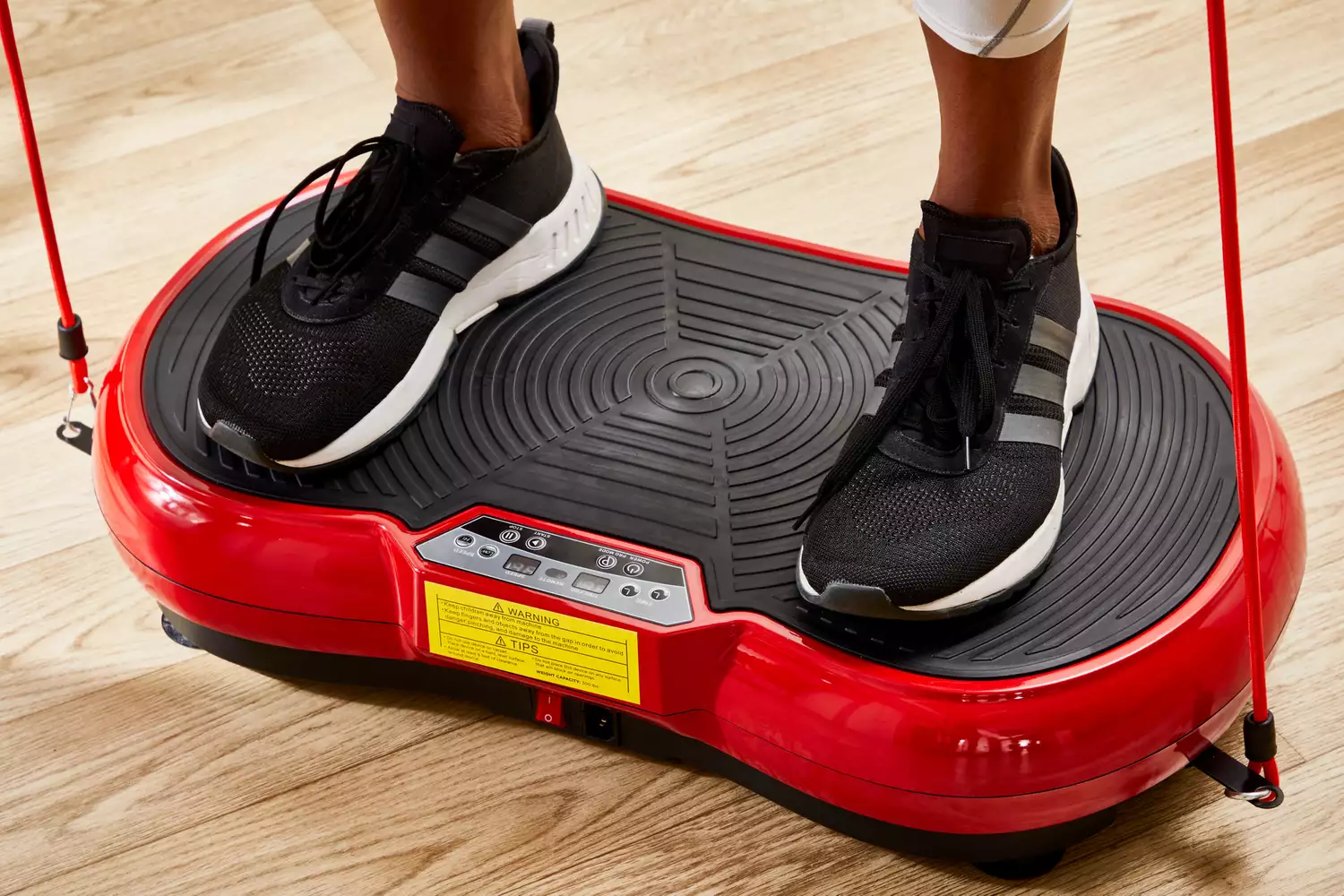 A person stands on the Super Deal Vibration Plate Exercise Machine