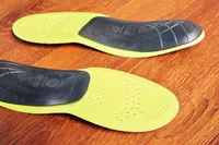 Bottoms of Superfeet Run Support Low Arch Shoe Inserts displayed on a wood floor