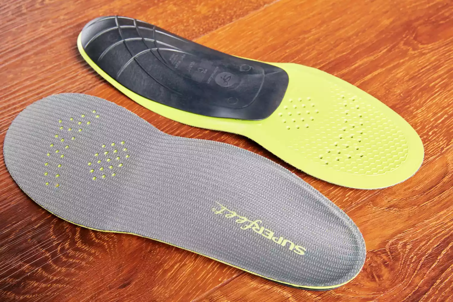 Top and bottom of Superfeet Run Support Low Arch Shoe Inserts displayed on a wood surface
