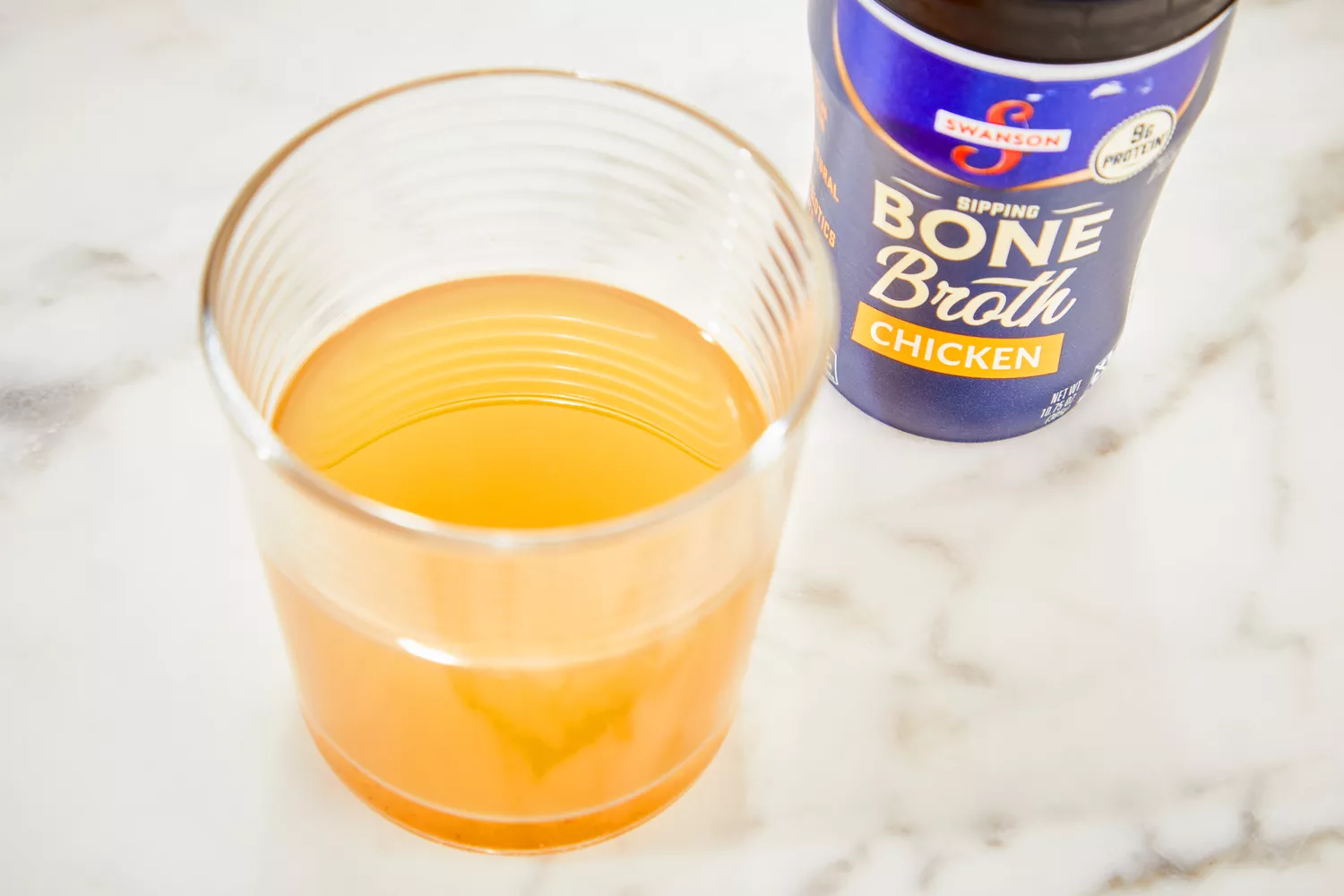 A glass of Swanson Sipping Chicken Bone Broth 