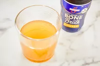 A glass of Swanson Sipping Chicken Bone Broth 
