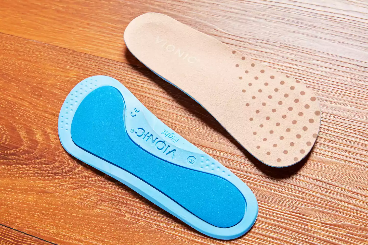 Top and bottom of Vionic Slimfit Orthotic Insoles displayed on a wood floor