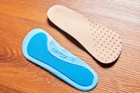 Top and bottom of Vionic Slimfit Orthotic Insoles displayed on a wood floor