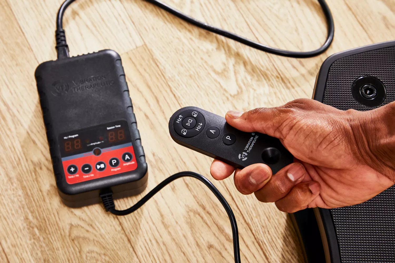 A hand presses a button on the VT Vibration Therapeutic Frequency Vibration Plate