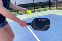 A person hits a ball with the Diadem Icon Infinity Pro Pickleball Paddle