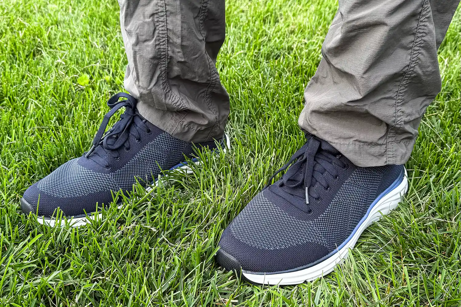 A person wearing Dr. Scholl's Men's Feel Ready Lace Up Sneakers standing on grass