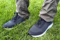 A person wearing Dr. Scholl's Men's Feel Ready Lace Up Sneakers standing on grass