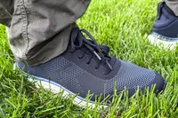 A person wearing Dr. Scholl's Men's Feel Ready Lace Up Sneakers on grass