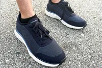 A person wearing Dr. Scholl's Men's Feel Ready Lace Up Sneakers standing on asphalt