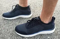 A pair of Dr. Scholl's Men's Feel Ready Lace Up Sneakers worn outdoors