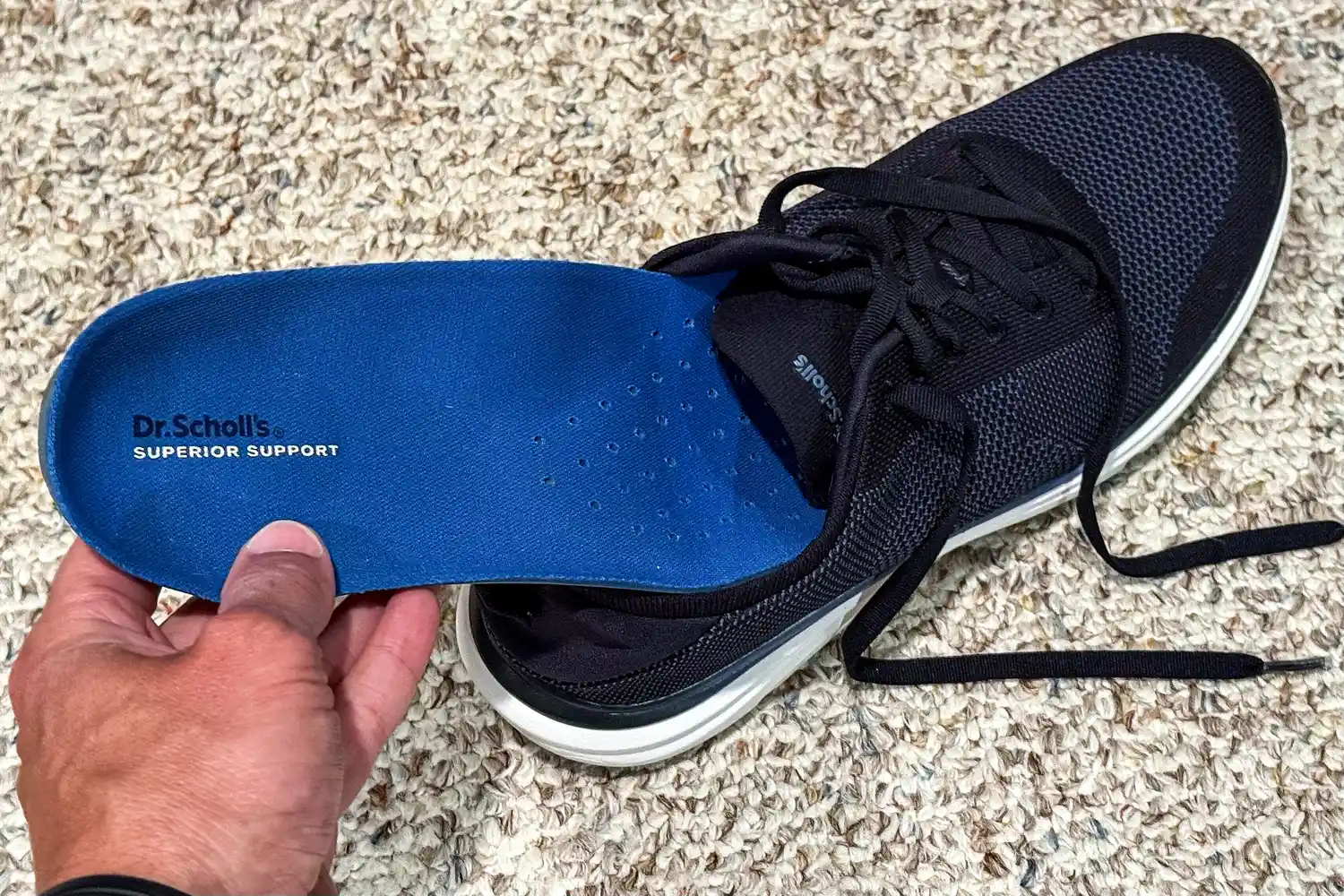 A person placing an insole into the Dr. Scholl's Men's Feel Ready Lace Up Sneaker