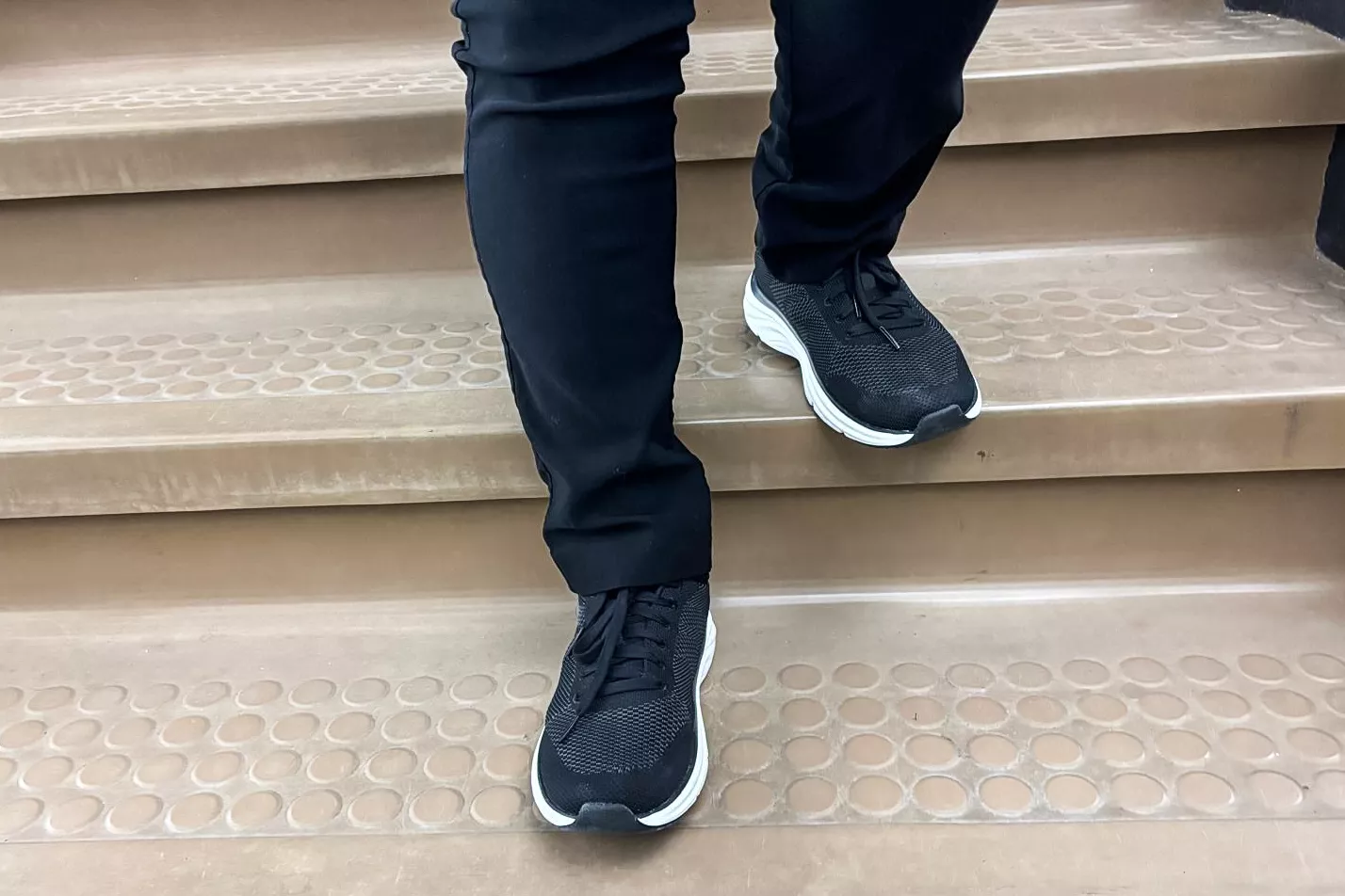 A close-up of a person's legs walking on stairs in the Dr. Scholl's Women's Feel Support Lace Up Sneakers