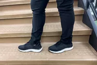 Two legs posed on stairs while wearing the Dr. Scholl's Women's Feel Support Lace Up Sneakers