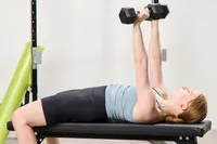A person does chest presses using the Bells of Steel Ergo Rubber Hex Dumbbells