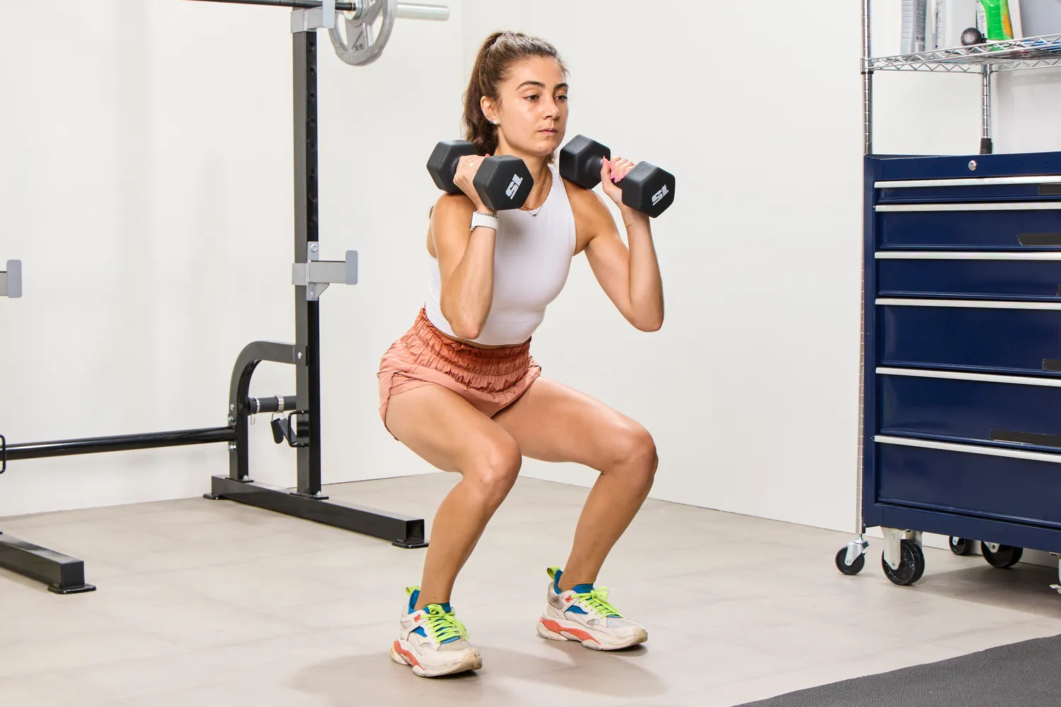 A person does squats with the CAP Barbell Neoprene Dumbbells
