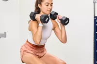 A person squats with the CAP Barbell Neoprene Dumbbells