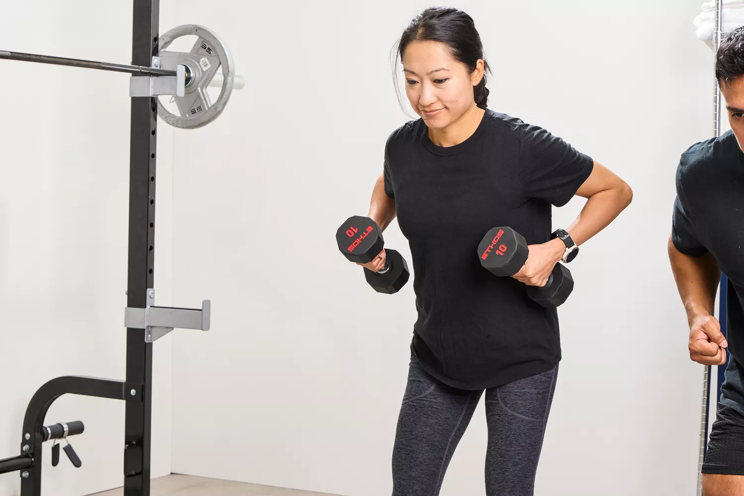 A person lifts the ETHOS Rubber Hex Dumbbells during exercise