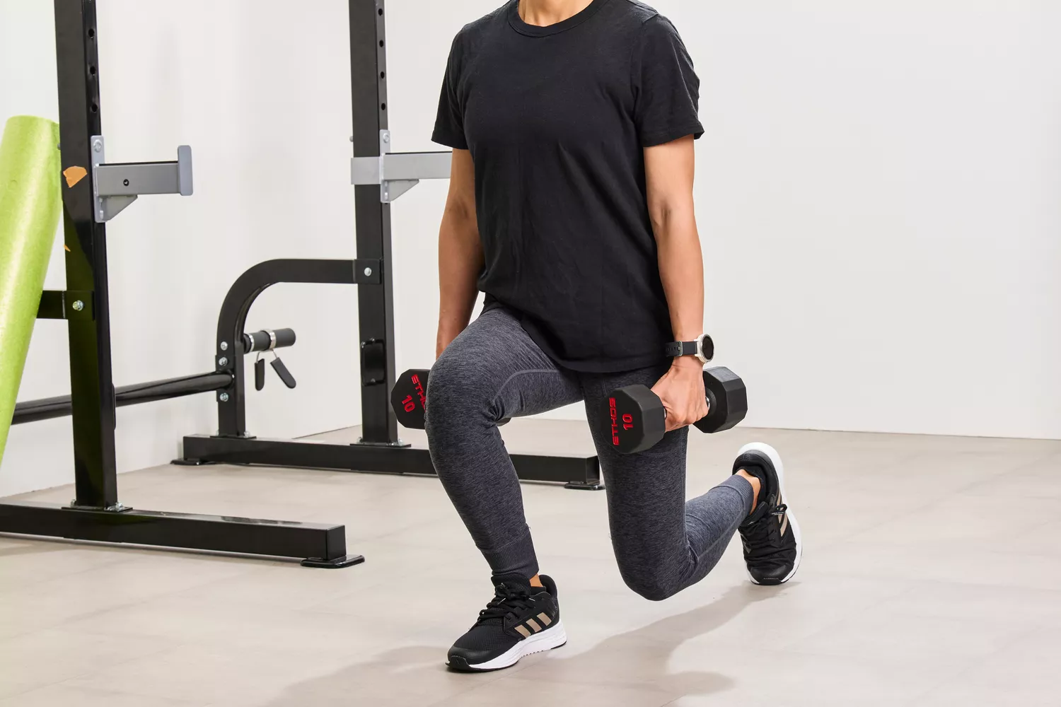 A person lunges with the ETHOS Rubber Hex Dumbbells