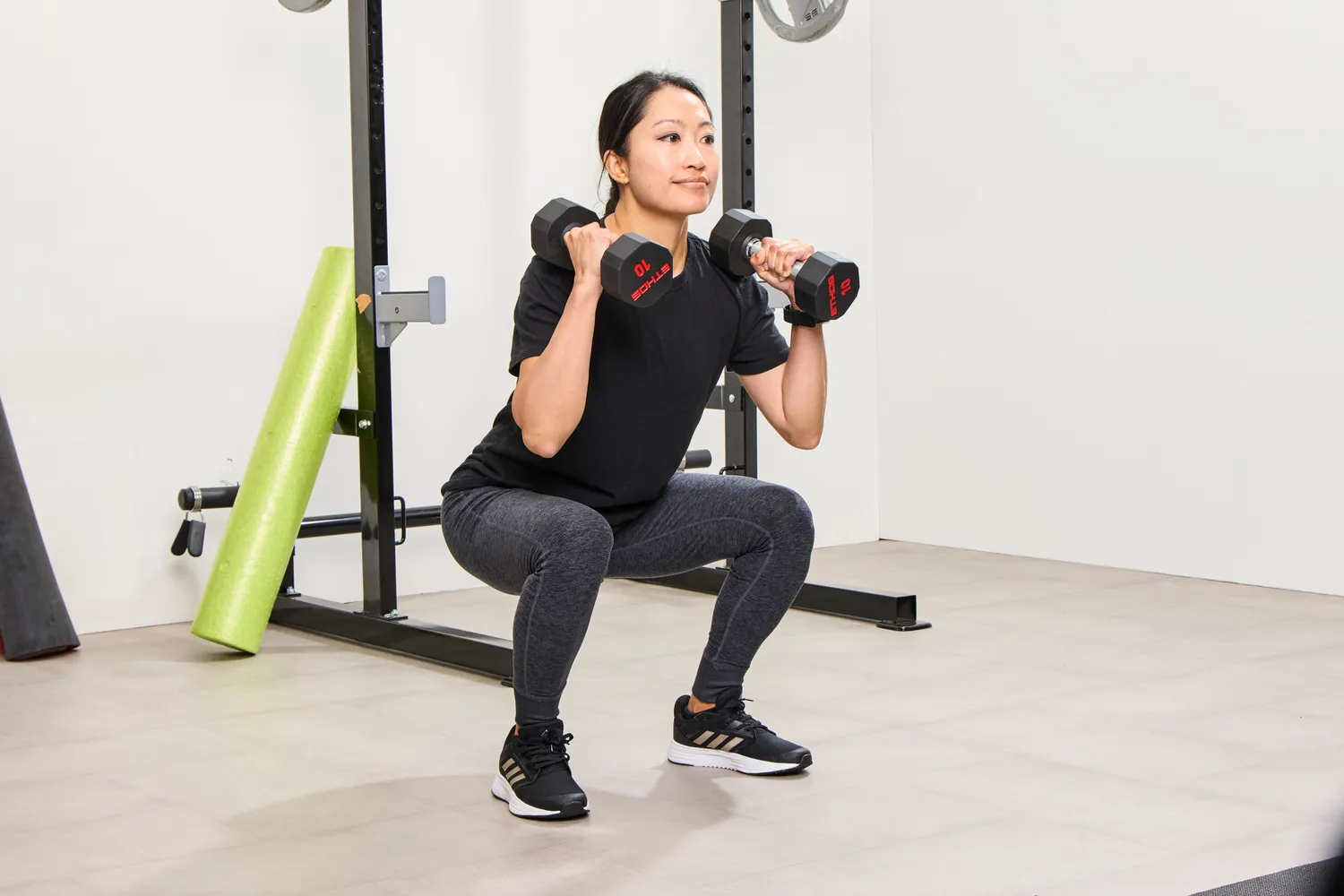 A person squats using the ETHOS Rubber Hex Dumbbells