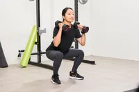 A person squats using the ETHOS Rubber Hex Dumbbells