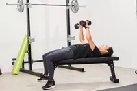 A person does chest presses using the ETHOS Rubber Hex Dumbbells