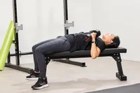 A person does chest presses using the ETHOS Rubber Hex Dumbbells