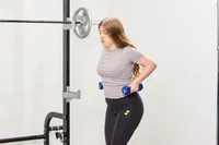 A person exercises using the JFIT Dumbbell Set with Rack