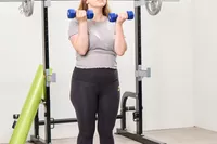 A person does arm curls using the JFIT Dumbbell Set with Rack