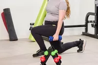 A person does lunges while holding the JFIT Dumbbell Set with Rack