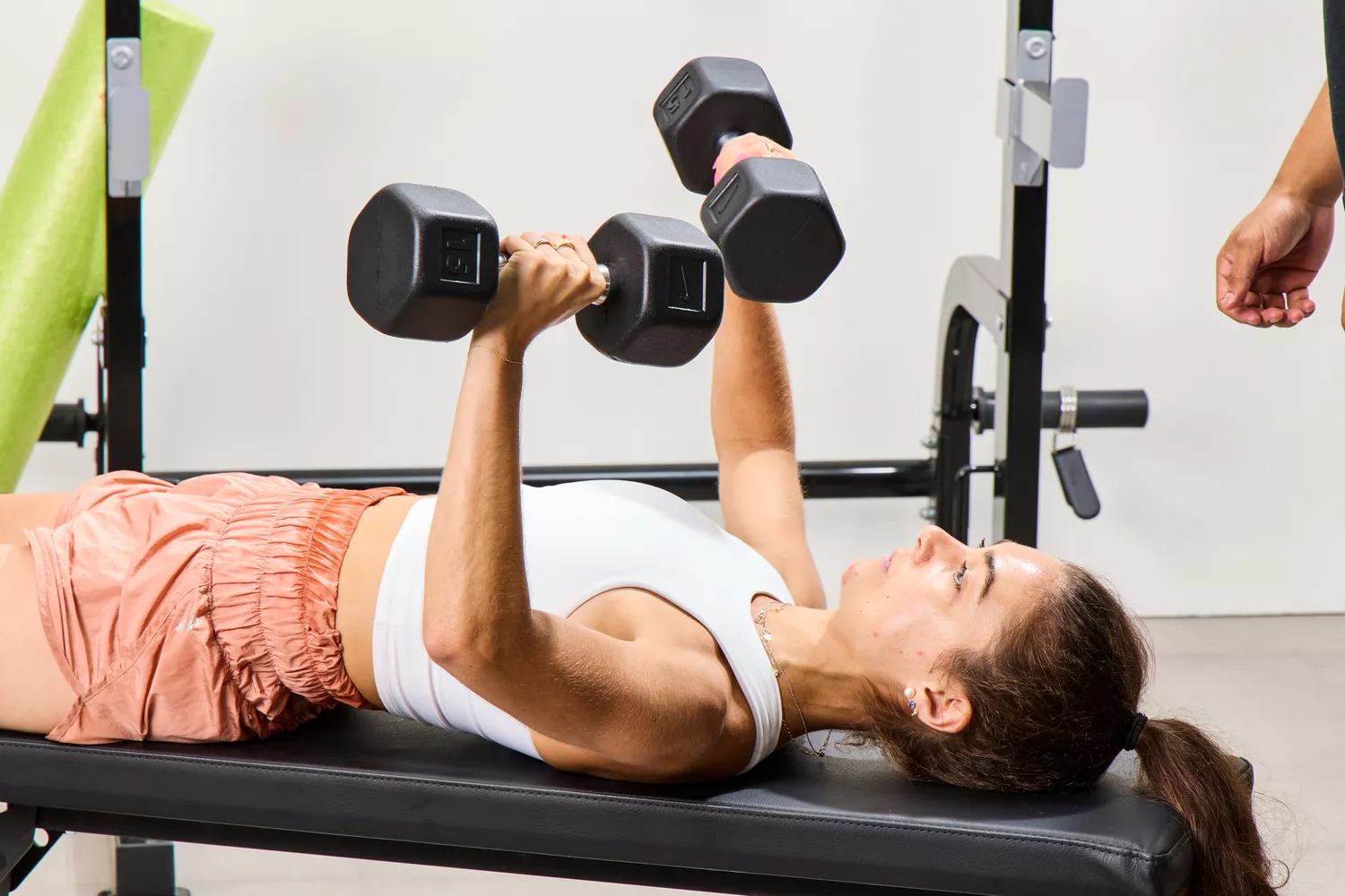 A person lifts Nike Dumbbells on a weight bench