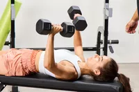 A person lifts Nike Dumbbells on a weight bench