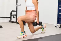 A person squats while holding the Nike Dumbbells