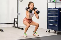 A person squats while holding the Nike Dumbbells