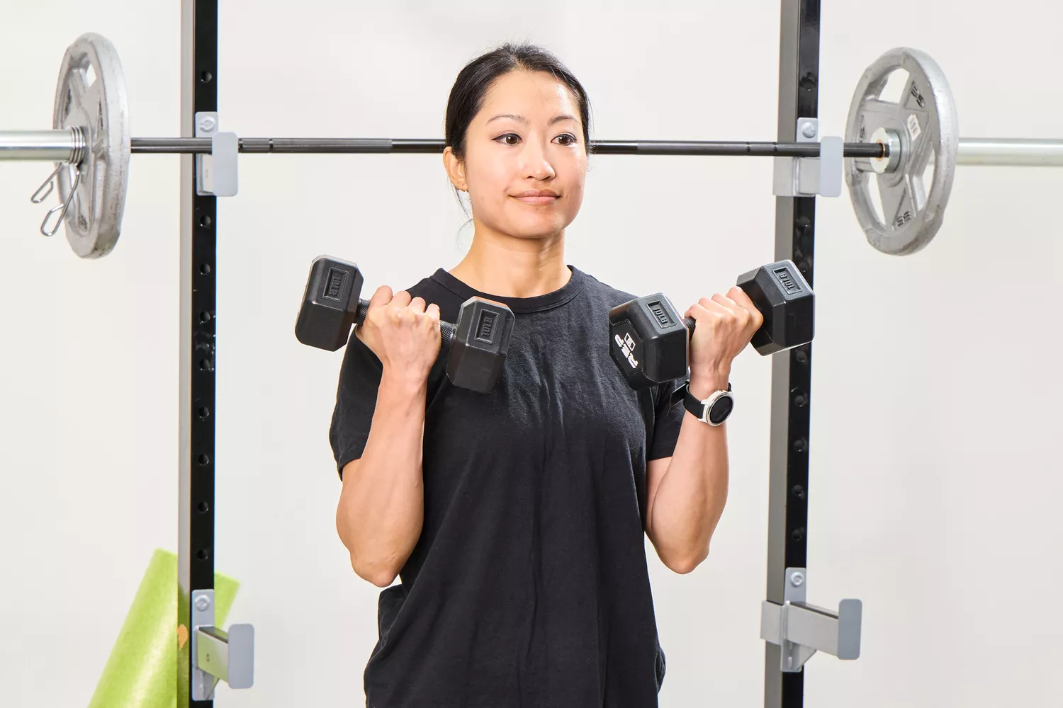 A person lifts the REP Fitness Rubber Coated Dumbbells during exercise