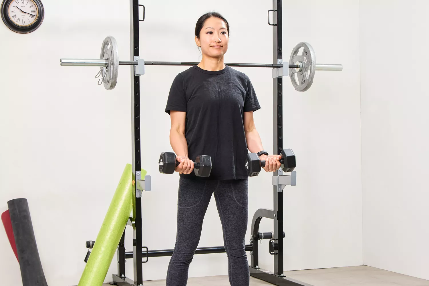 A person lifts the REP Fitness Rubber Coated Dumbbells