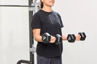 A person does arm curls using the REP Fitness Rubber Coated Dumbbells