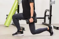 A person lunges while holding the REP Fitness Rubber Coated Dumbbells