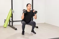 A person squats while holding the REP Fitness Rubber Coated Dumbbells