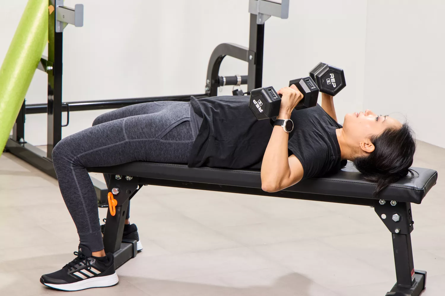 A person lifts the REP Fitness Rubber Coated Dumbbells during exercise