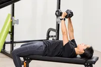 A person does chest presses using the REP Fitness Rubber Coated Dumbbells