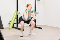 A person holds the Yes4All Neoprene Coated Dumbbells while squatting