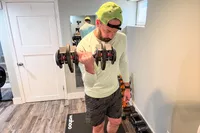 A person lifts up the Echelon Strength Adjustable Dumbbells 752 with Stand