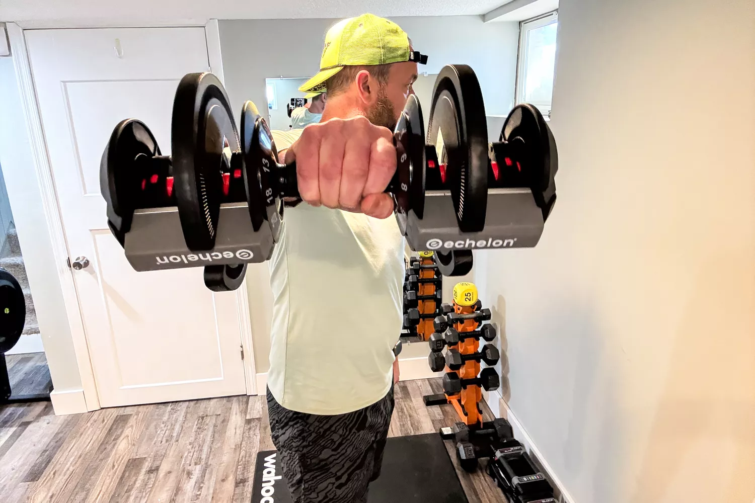A person holds up the Echelon Strength Adjustable Dumbbells 752 with Stand