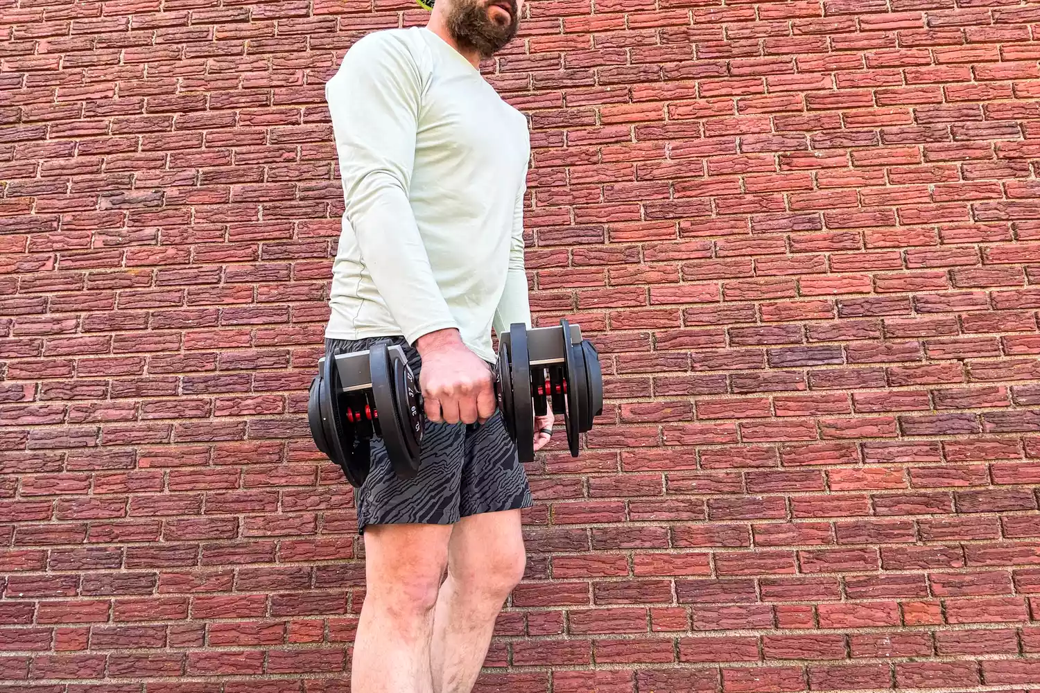 A person lifts the Echelon Strength Adjustable Dumbbells 752 with Stand