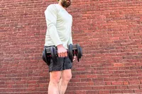 A person lifts the Echelon Strength Adjustable Dumbbells 752 with Stand