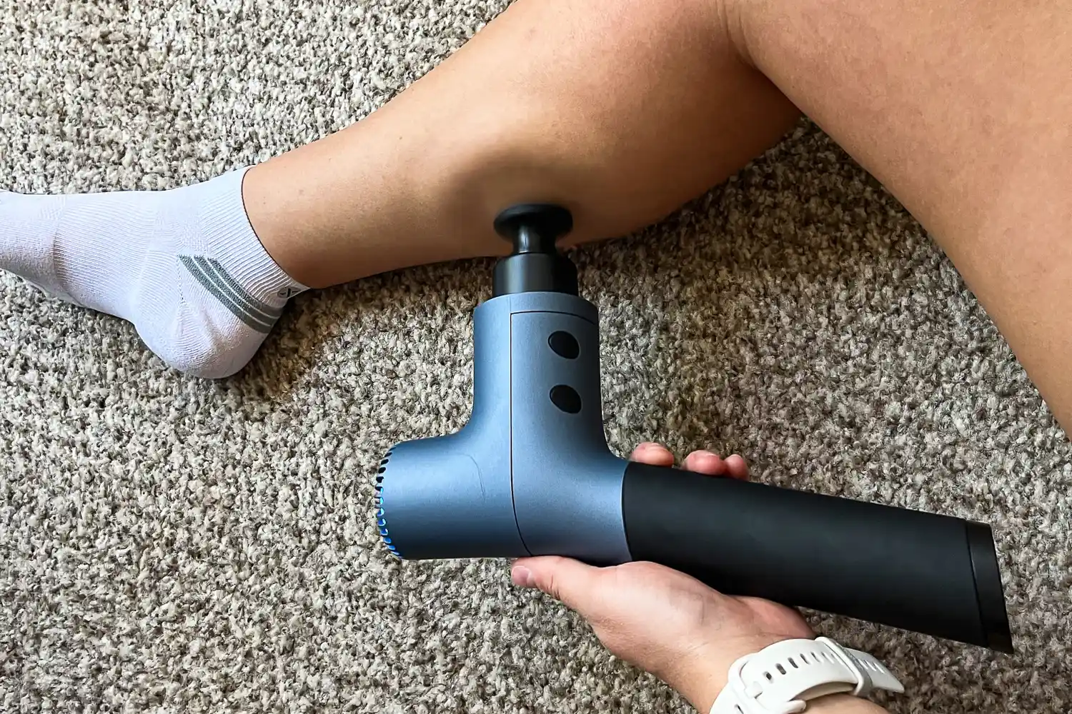 A person uses the Ekrin 365 Massage Gun on their calf