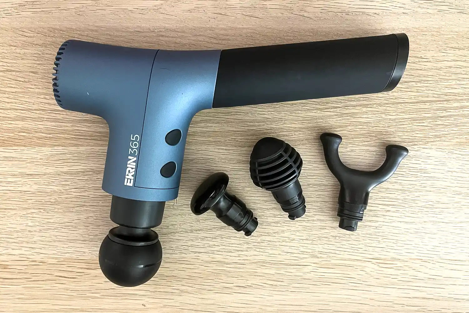 The Ekrin 365 Massage Gun with attachment heads displayed on a wooden surface