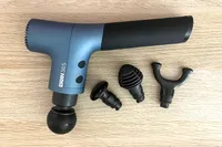 The Ekrin 365 Massage Gun with attachment heads displayed on a wooden surface