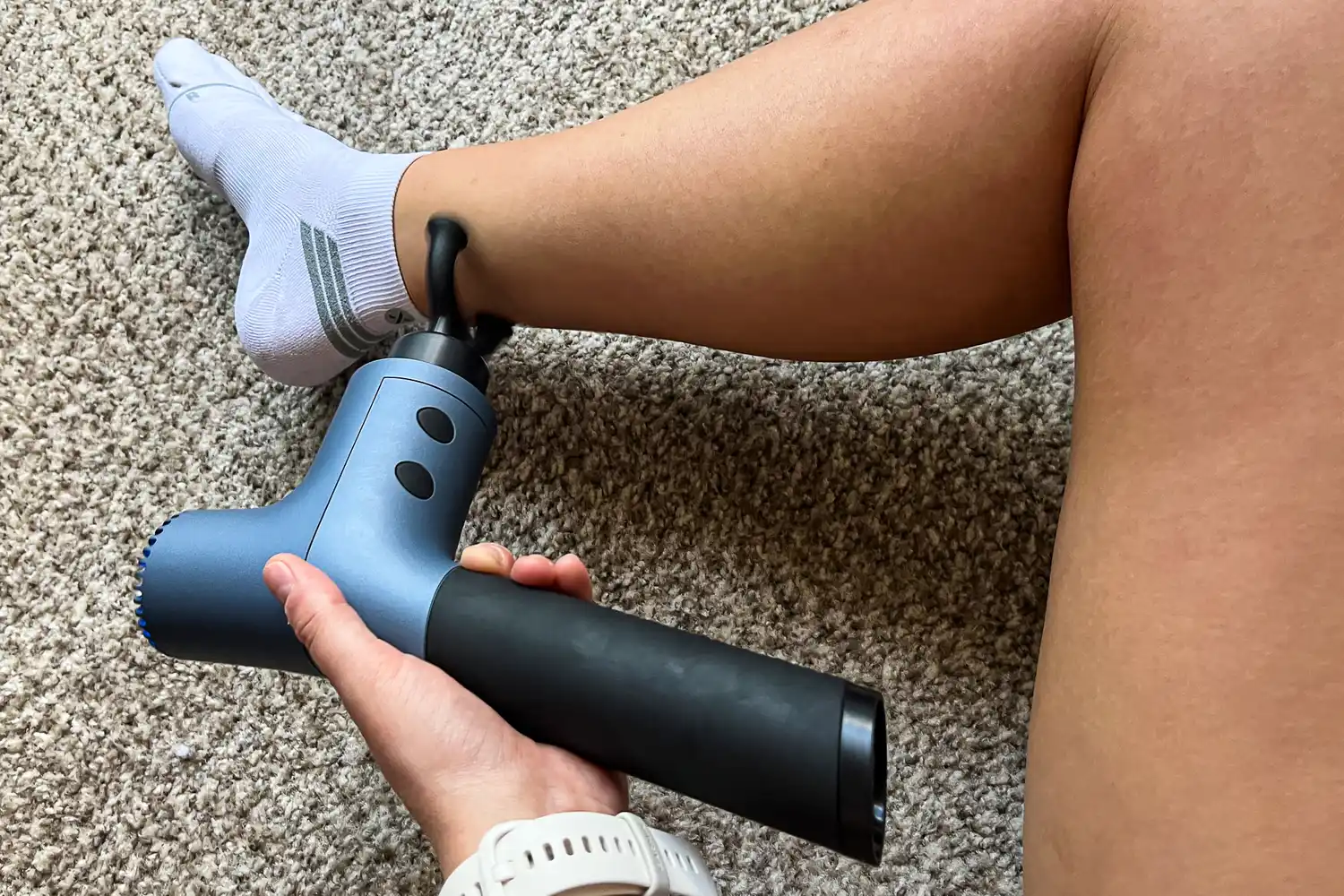 A person uses the Ekrin 365 Massage Gun on their ankle