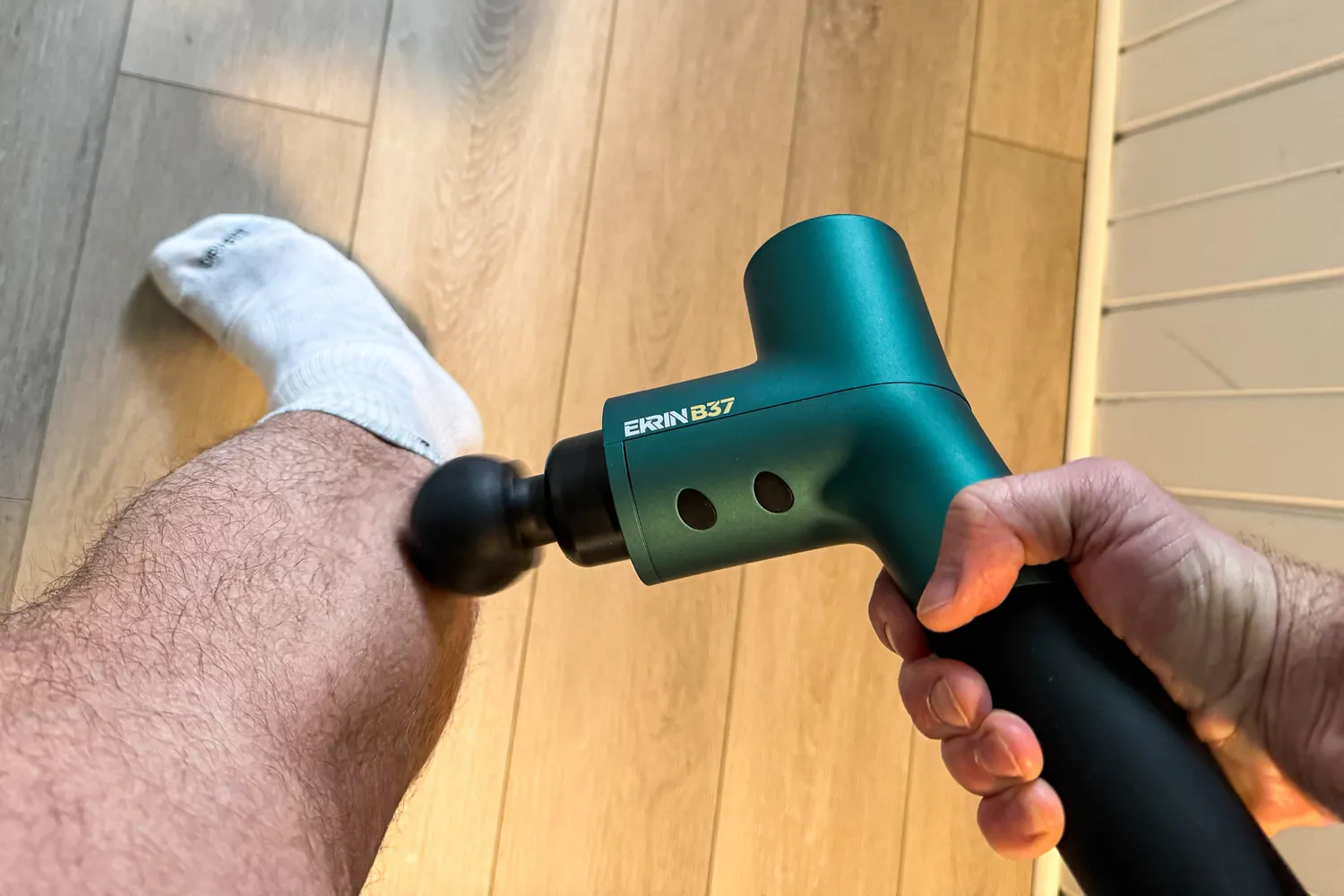 A person uses the Ekrin B37 Massage Gun on their leg